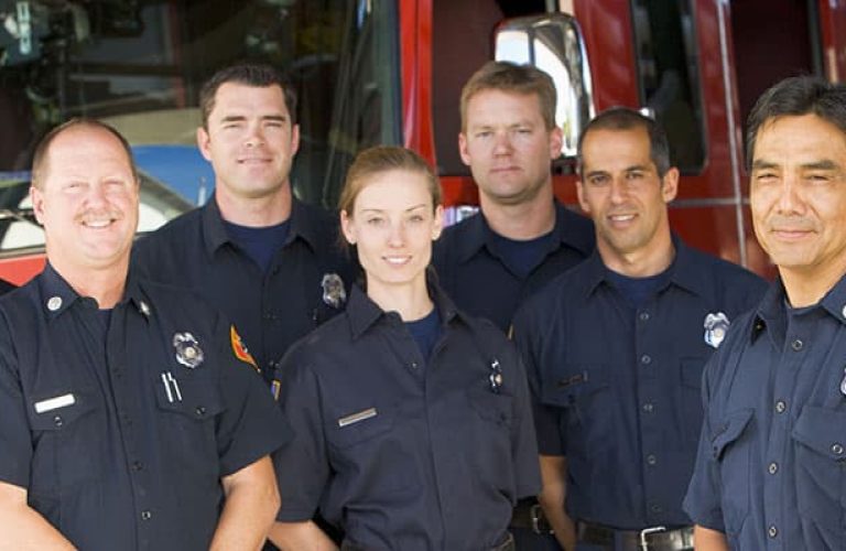 Portrait of firefighters standing by a fire engine